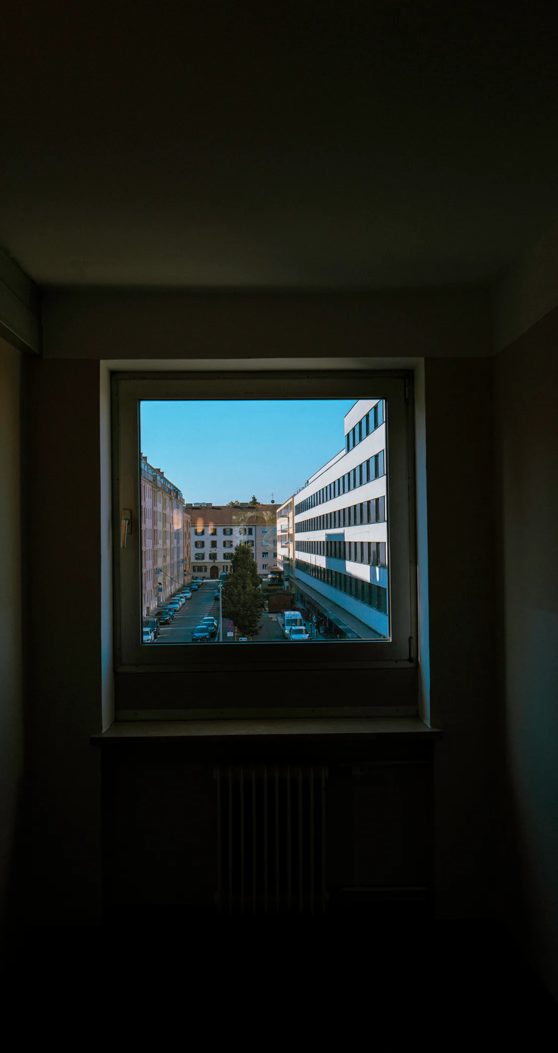City courtyard framed by a window in a dark room